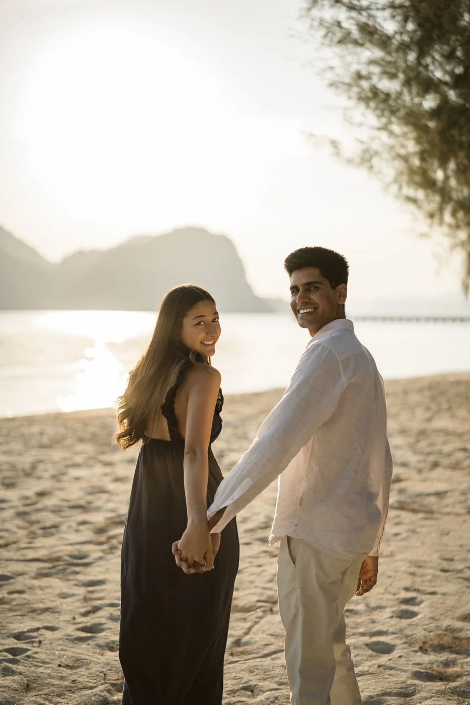 Alisha and Kunal holding hands on the beach at sunset