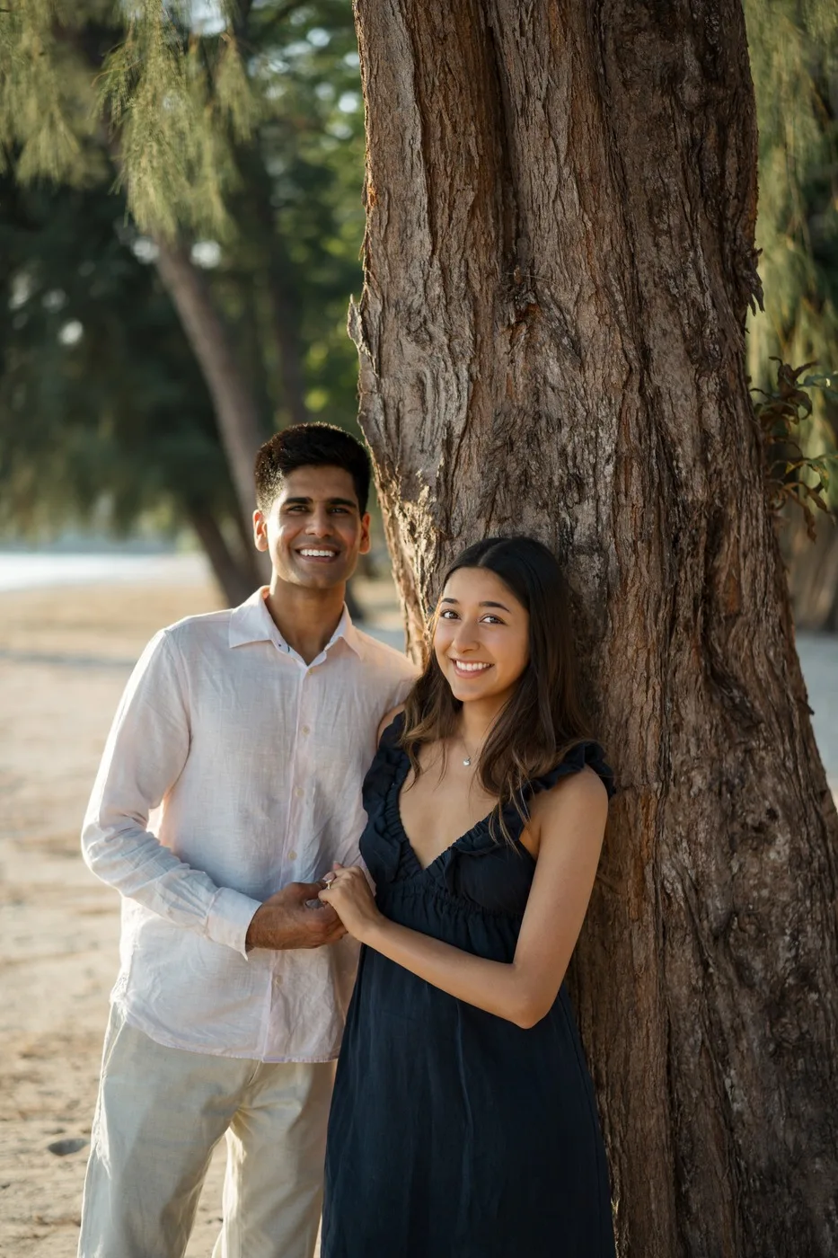 Alisha and Kunal smiling together beside a tree by the lake